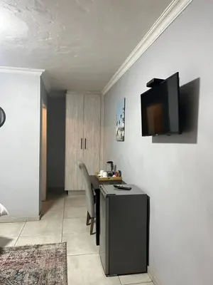 a room with a table and a television on the wall at Mogoma Guesthouse in Witbank