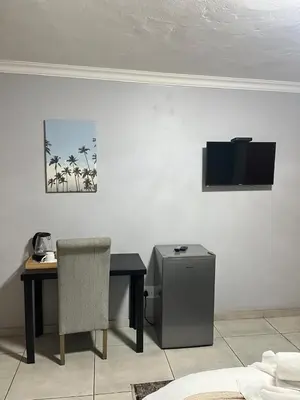 a desk with a chair and a television on a wall at Mogoma Guesthouse in Witbank