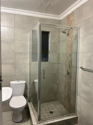 a bathroom with a toilet and a glass shower at Mogoma Guesthouse in Witbank