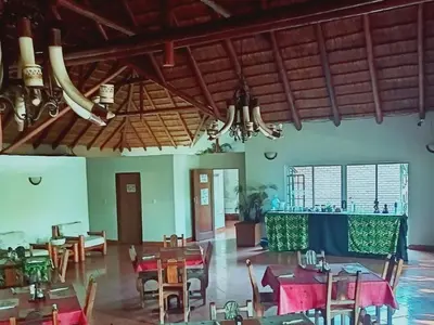 a dining room with tables and chairs and chandeliers at Bonamanzi Guesthouse in Burgersfort