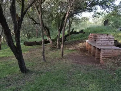 a stack of bricks in a field with trees at Bonamanzi Guesthouse in Burgersfort