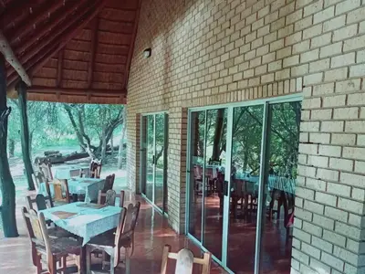 a dining room with tables and chairs and a brick wall at Bonamanzi Guesthouse in Burgersfort