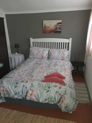 a bedroom with a bed with red pillows at Chalet 6 At Cynthias Country in Hartbeespoort