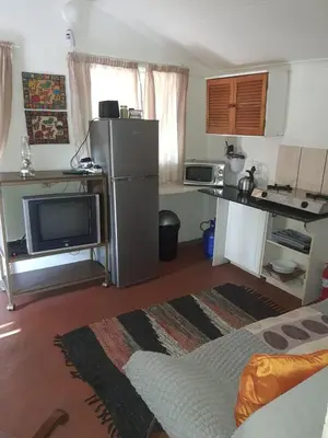 a room with a kitchen with a refrigerator and a tv at Chalet 6 At Cynthias Country in Hartbeespoort
