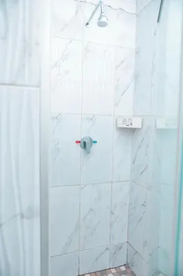 a bathroom with a shower with white marble tiles at Falcon Lodge PK in Bela-Bela