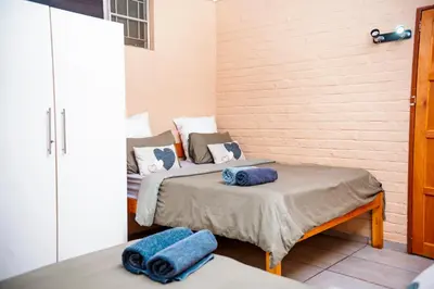 two beds in a room with blue towels on them at Falcon Lodge PK in Bela-Bela