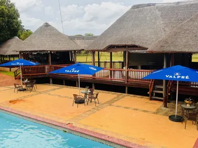 a resort with chairs and umbrellas next to a pool at Falcon Lodge PK in Bela-Bela