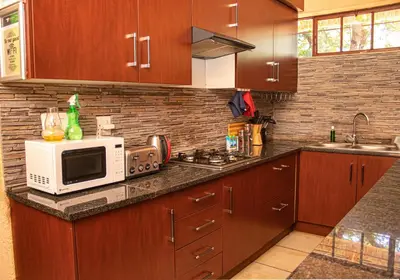 a kitchen with wooden cabinets and a microwave oven at Falcon Lodge Bela in Bela-Bela