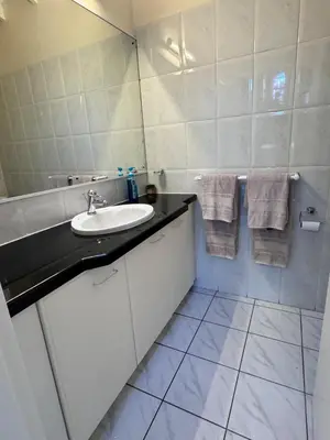 a white bathroom with a sink and a mirror at Olives by Agnes 33 in Hartbeespoort
