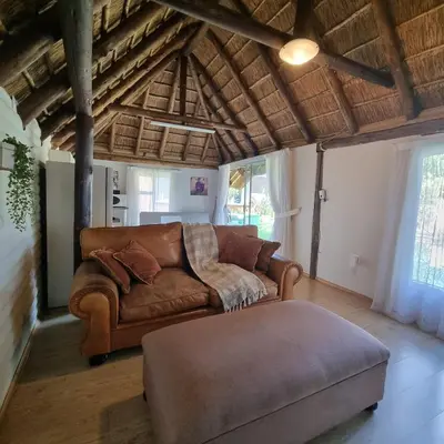 a living room with a brown couch and a ottoman at Kruin cottage in Pretoria
