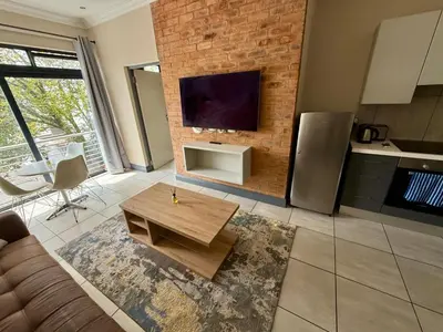 a living room with a couch and a tv on a brick wall at Junction 30 in Pretoria