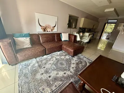 a living room with a brown couch and a table at Lynwood 919 in Pretoria