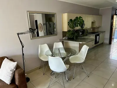 a living room with a glass table and white chairs at Lynwood 919 in Pretoria
