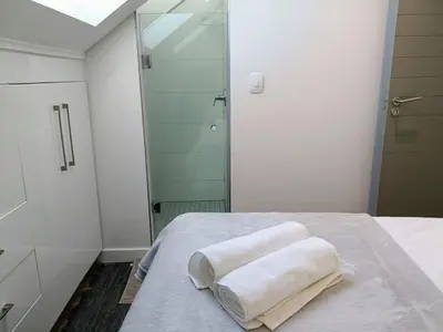 a bathroom with a shower and two towels on a bed at Menlo Gate in Pretoria