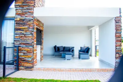a patio with two blue chairs and a brick wall at Batau Villa in Naboomspruit