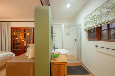 a bathroom with a bed and a sink and a shower at Stay at Royal in Marloth Park