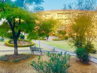 a park with a bench and a tree and a building at Phoenix Rising Apartment in Midrand