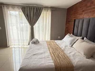 a bedroom with a large bed with a large window at Home Away Nest in Witbank