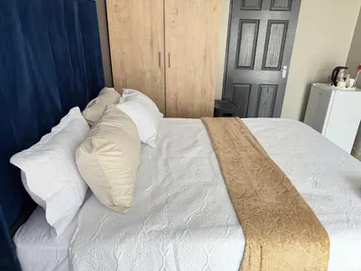 a white bed with white pillows and a blue headboard at Home Away Nest in Witbank