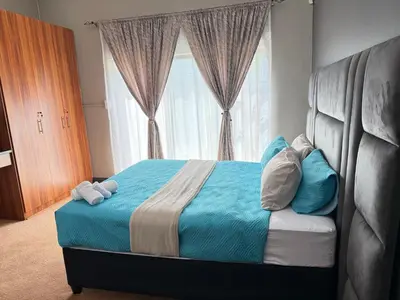 a bedroom with a blue bed with a large window at Home Away Nest in Witbank