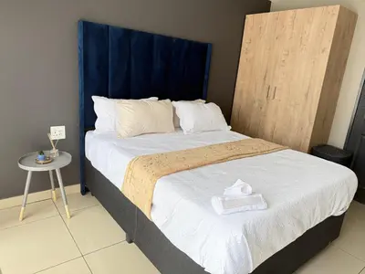 a bedroom with a large bed with a blue headboard at Home Away Nest in Witbank