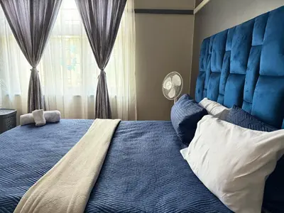 a bedroom with a blue bed with a large blue headboard at Home Away Nest in Witbank
