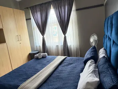 a bedroom with a blue bed with a window at Home Away Nest in Witbank