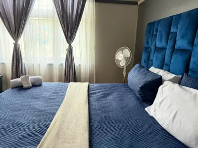 a bedroom with a blue bed with a blue headboard and a window at Home Away Nest in Witbank