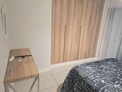 a bedroom with a bed and a wooden table at KD Homes in Pretoria