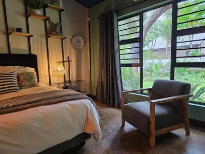a bedroom with a bed and a chair and a window at Stayfit 03 in Polokwane