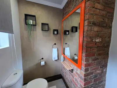 a bathroom with a white toilet and a brick wall at Stayfit 03 in Polokwane