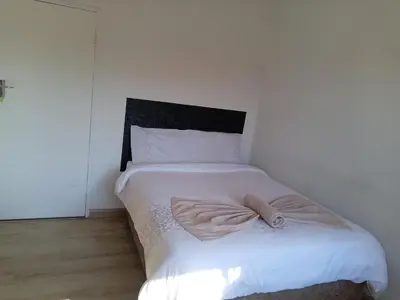 a bedroom with a white bed with a black headboard at TRIANGLE STARS Guest House in Kempton Park