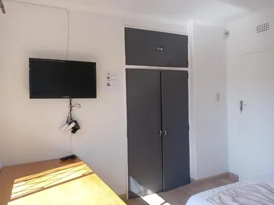 a bedroom with a tv on the wall and a bed at TRIANGLE STARS Guest House in Kempton Park