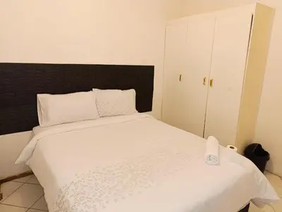 a bedroom with a white bed with a black headboard at TRIANGLE STARS Guest House in Kempton Park