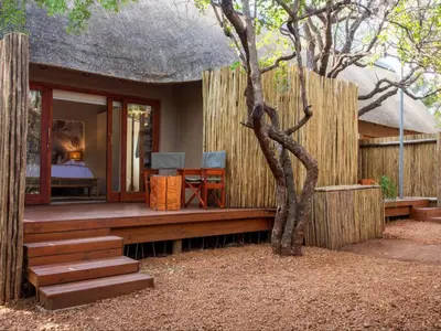 a house with a deck with a bed and a tree at Etnika Manor House in Hoedspruit