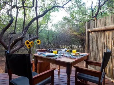 a wooden table and chairs on a deck at Etnika Manor House in Hoedspruit