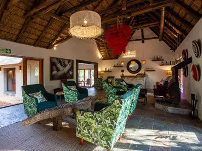 a living room with couches and a chandelier at Etnika Manor House in Hoedspruit