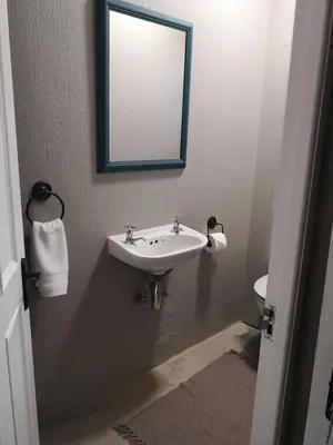 a bathroom with a sink and a mirror and a toilet at A cozy, artistic suburban-stay at Alice in Africa in Rooihuiskraal