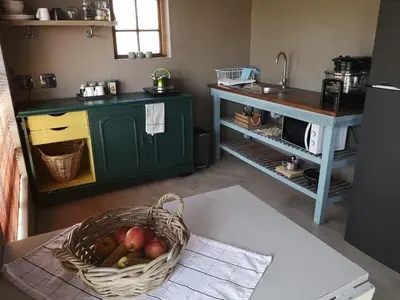 a kitchen with a basket of fruit on a table at A cozy, artistic suburban-stay at Alice in Africa in Rooihuiskraal