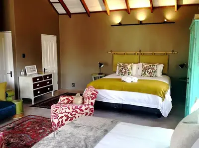 a bedroom with a large bed and a chair at A cozy, artistic suburban-stay at Alice in Africa in Rooihuiskraal