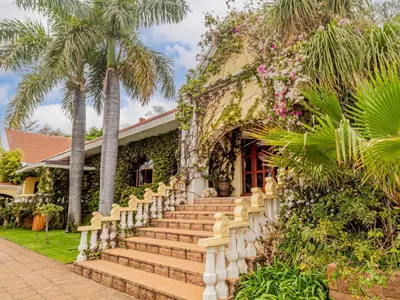 a house with stairs in front of it with palm trees at Casta Diva Boutique Hotel in Pretoria