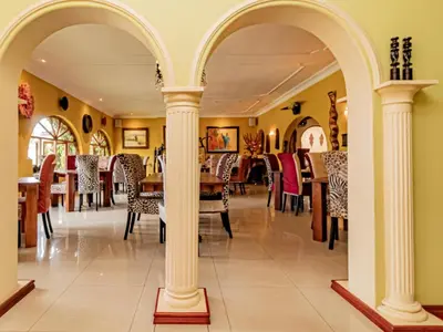 a restaurant with white columns and tables and chairs at Casta Diva Boutique Hotel in Pretoria