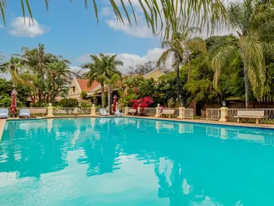 a large swimming pool with chairs and palm trees at Casta Diva Boutique Hotel in Pretoria