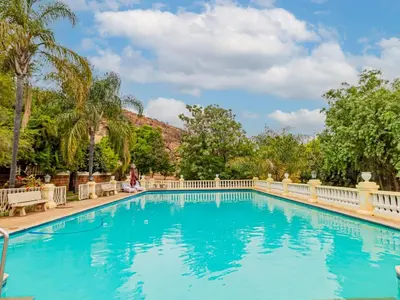 a swimming pool at a resort with palm trees at Casta Diva Boutique Hotel in Pretoria