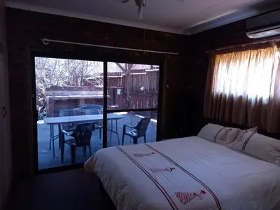 a bedroom with a bed and a balcony with a table at Leeupoort Bosvakansie in Leeupoort