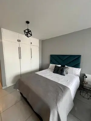 a bedroom with a large bed and white cabinets at Neat, instaworthy, self-checkin flat in Pretoria in Pretoria