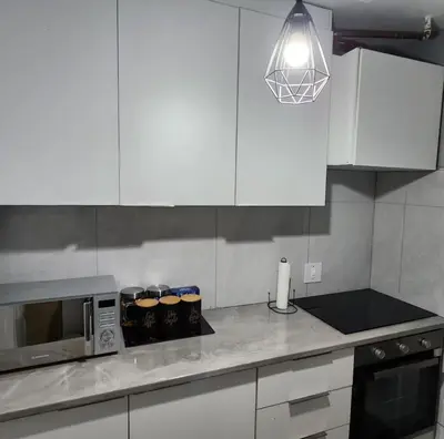 a kitchen with white cabinets and a microwave at Neat, instaworthy, self-checkin flat in Pretoria in Pretoria