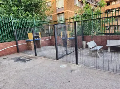 a fence with a bench in front of a building at Neat, instaworthy, self-checkin flat in Pretoria in Pretoria