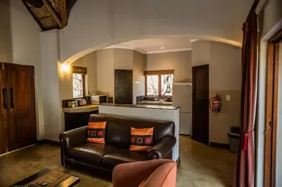a living room with a leather couch and a kitchen at Hoedspruit Raptors Lodge N16 in Hoedspruit