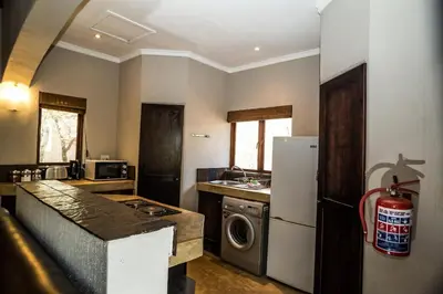 a kitchen with a refrigerator and a washer and dryer at Hoedspruit Raptors Lodge N16 in Hoedspruit